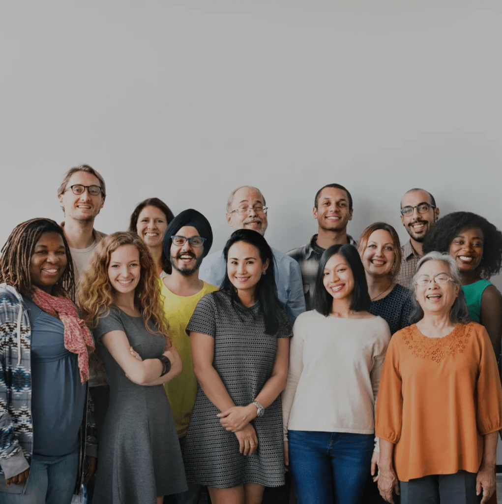 Two rows of diverse people satdning against a blank white wall for Dr. Liz Wilson - Diversity and inclusion expert consultant